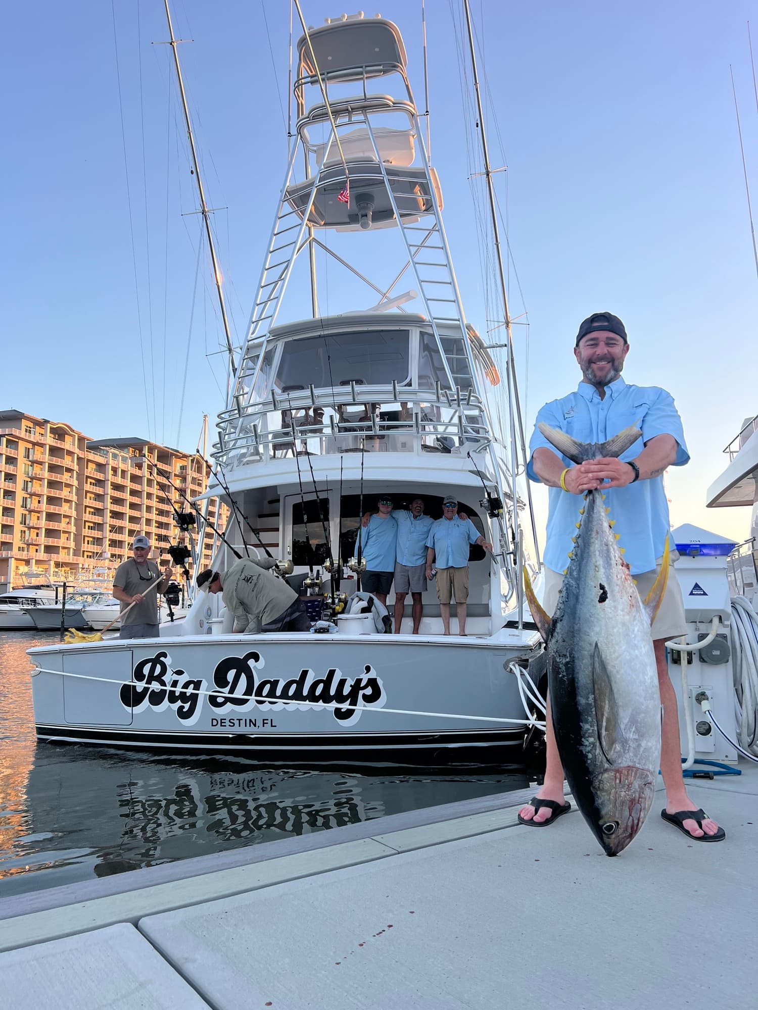 Angler at the dock with a trophy yellowfin tuna, Big Daddy's tower behind him