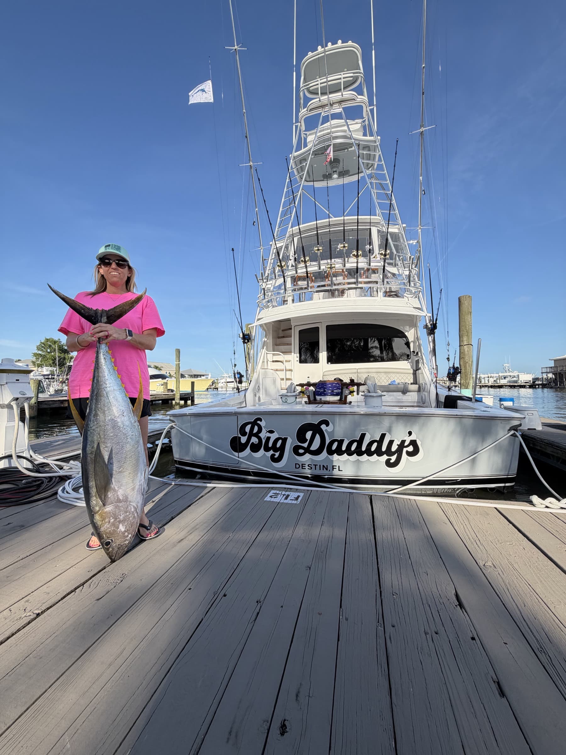 Angler in pink holding the trophy yellowfin tuna dockside, Big Daddy's at the berth behind